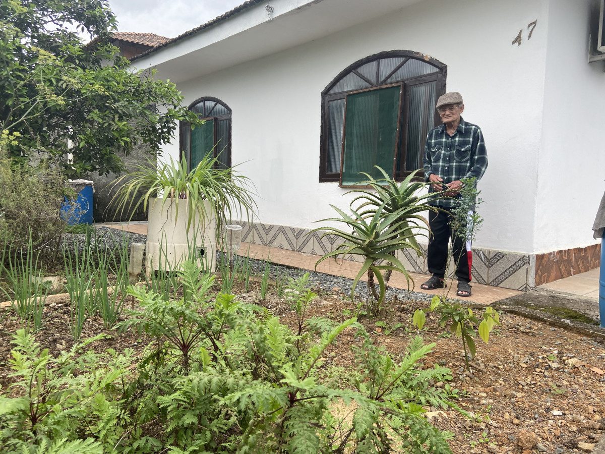 Martiniano em frente a casa mostra a horta repleta de plantas