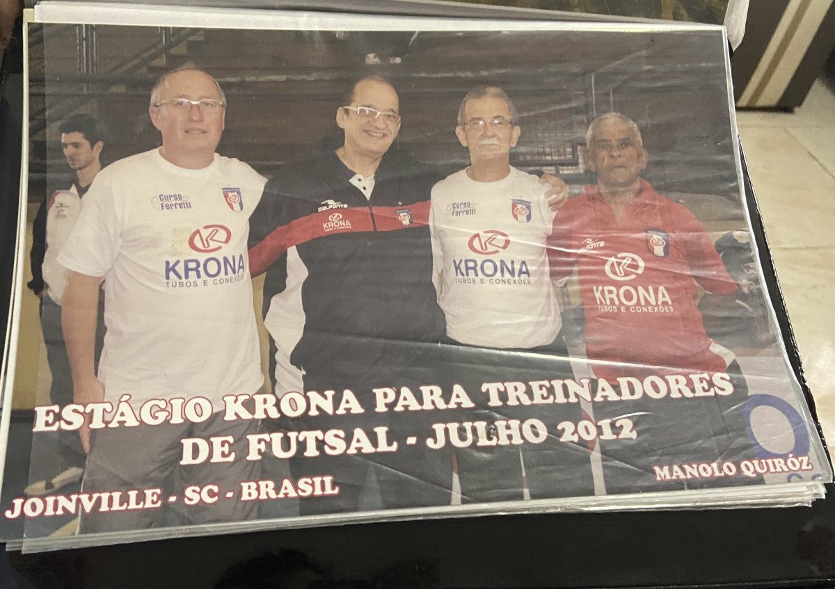 Zé e outros três homens com camisetas do JEC futsal. Na foto tem escrito "Estágio Krona para treinadores de futsal 2012, Joinville, SC, Brasil"