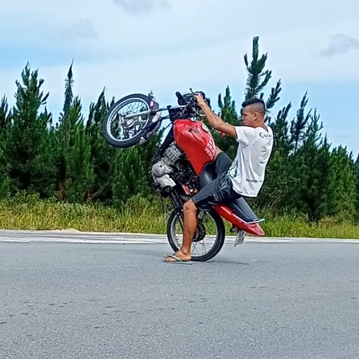 Deividy empinando uma moto vermelha