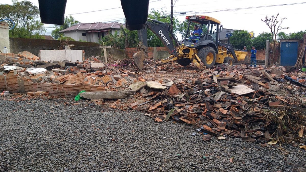 escavadeira limpendo o terreno cheio de materiais queimados