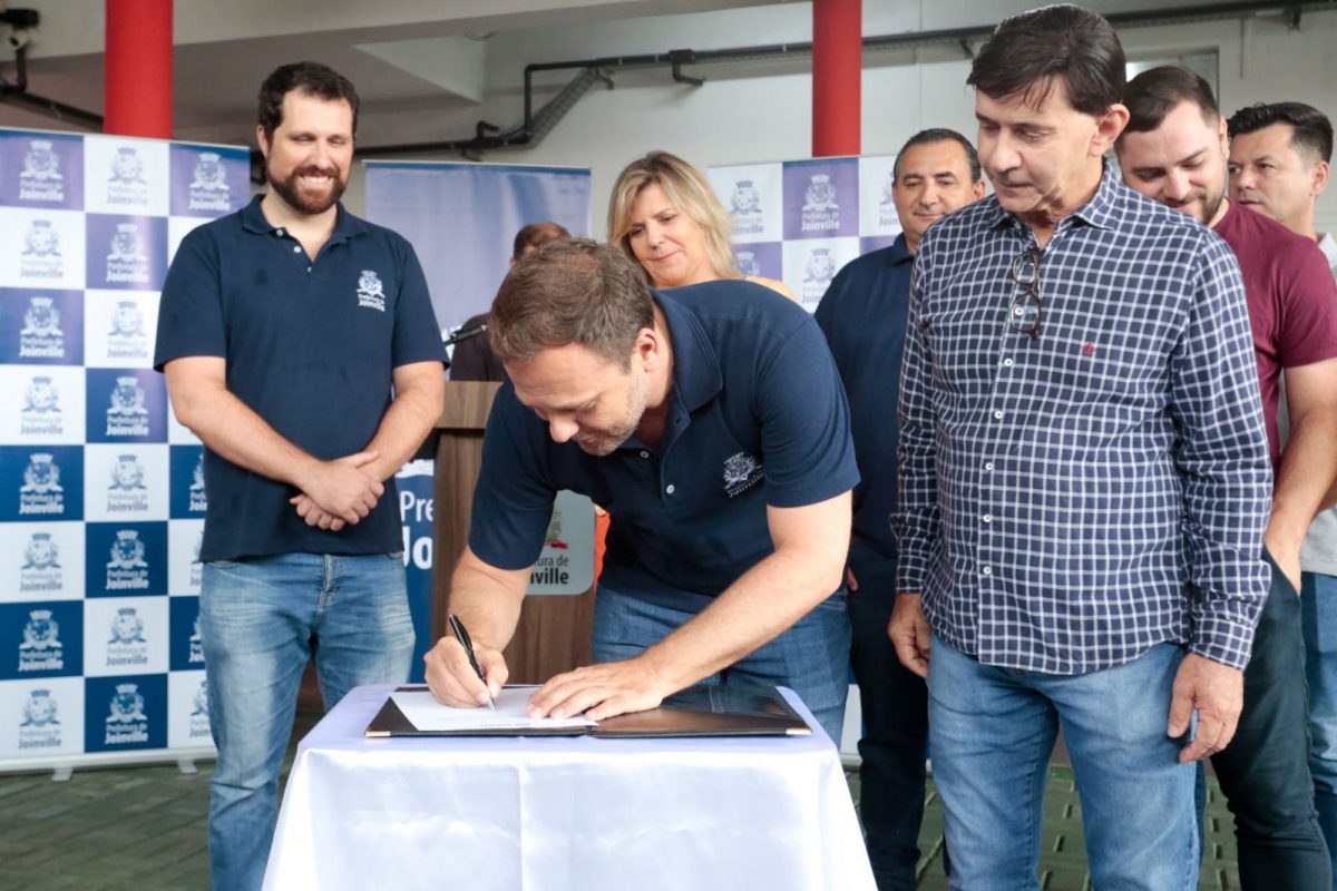 Diego Calegari na esquerda, prefeito assinando ordem, Rejane Gambin atrás. No lado direito, o de blusa xadrez é o vereador Kiko, atrás dele Tonezi e Erico. Mais ao fundo está Brandel