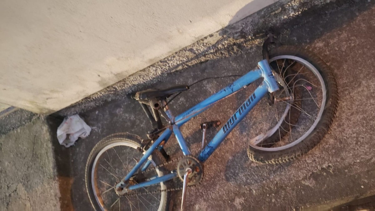 Bicicleta azul caída com a roda dianteira torta